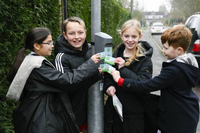 The image shows 4 children standing around a lamp post with a beat the street beat box, where they are swiping their cards, whilst looking at the camera.