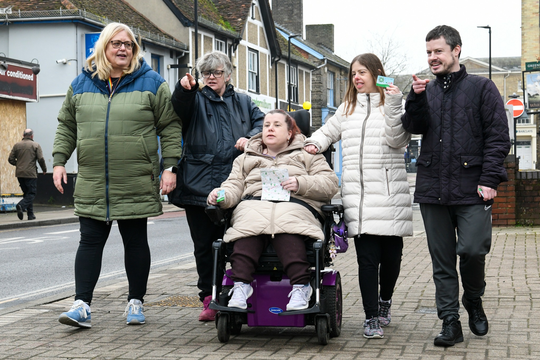 The image shows 5 five, 1 in a wheelchair and 4 walking in one direction.