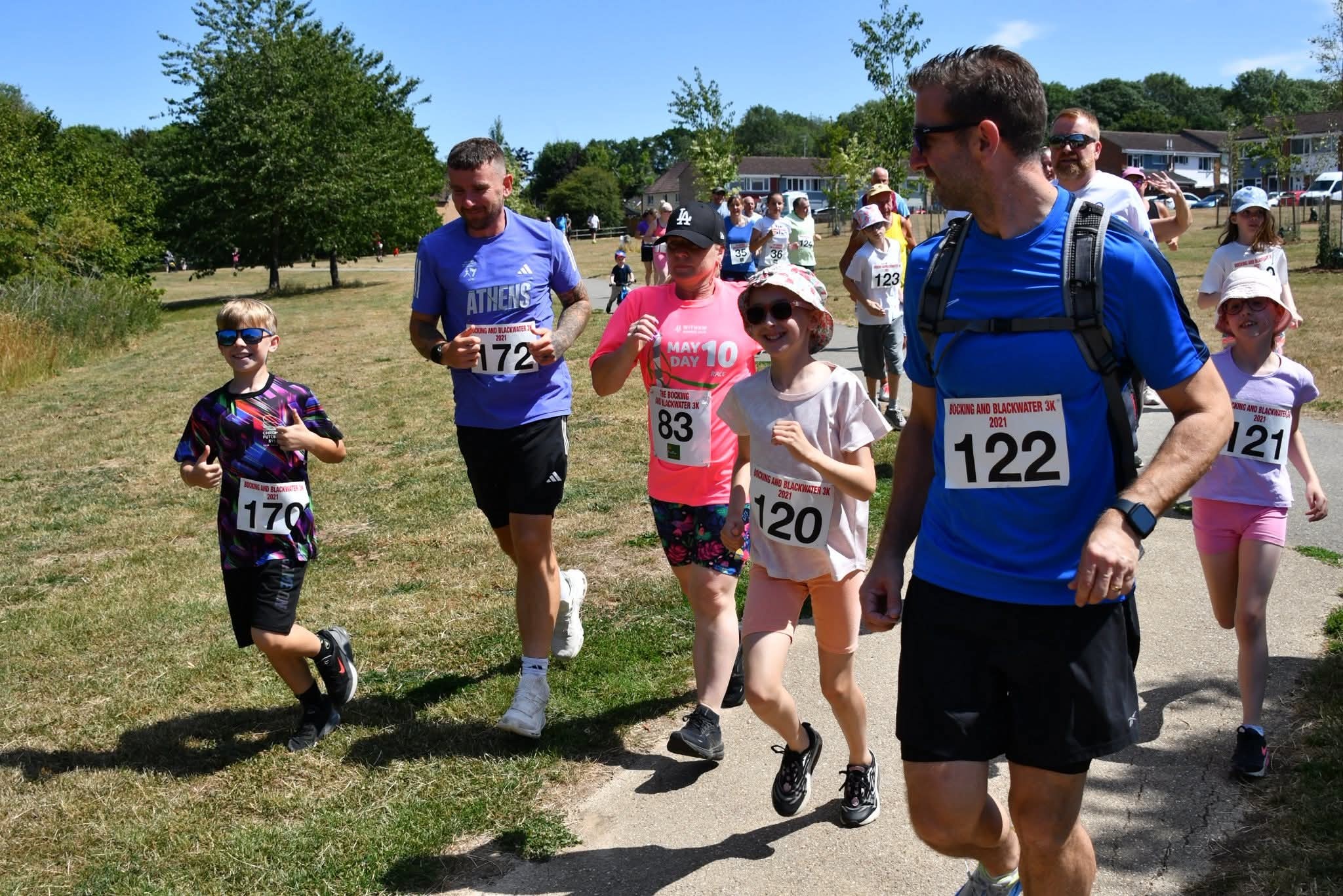 The image shows a group of people of all ages running in front of the camera.
