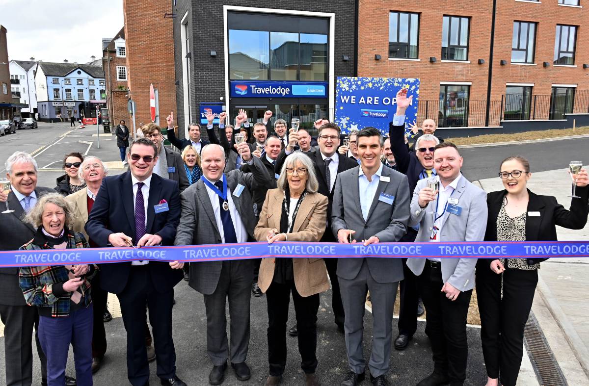 A group of people at an opening ceremony in front of the Travelodge in Braintree.