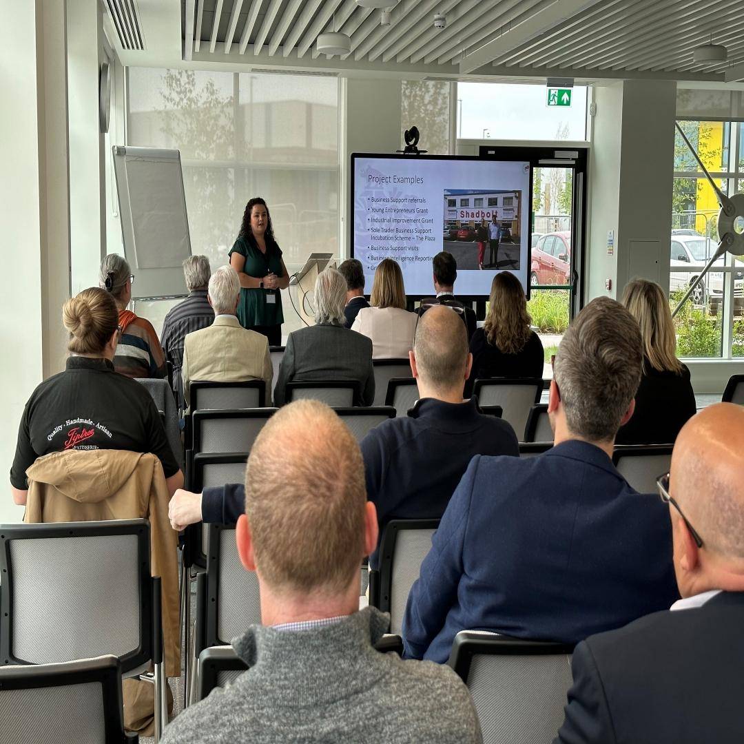 Danielle Eastlea presents at the front of a filled room.