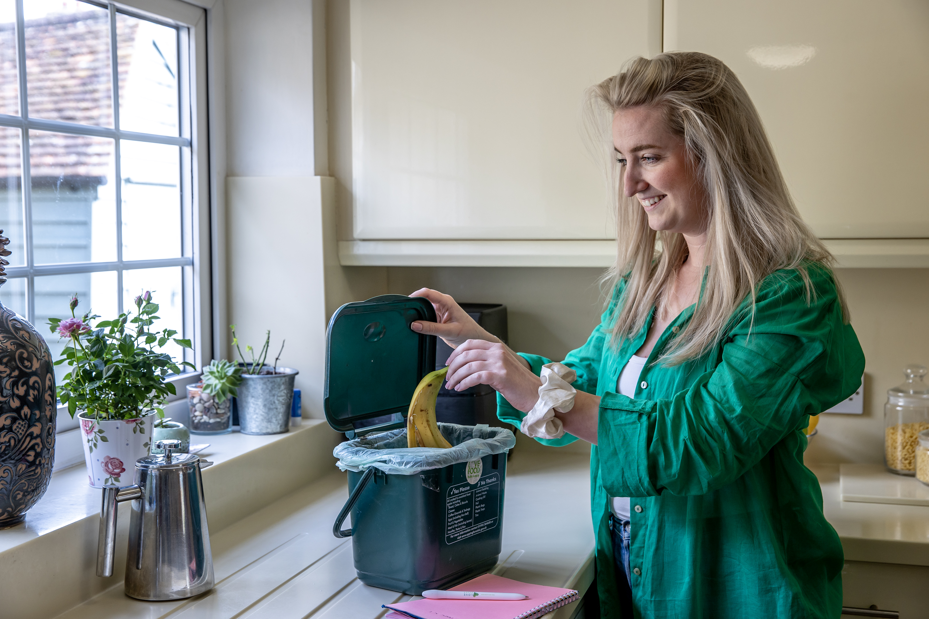 Image - a photo of a women putting food in her food waste bin.