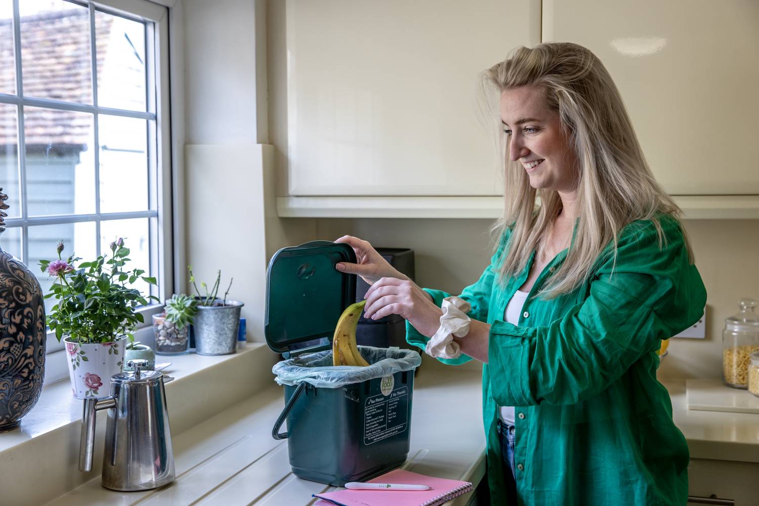 Image - a photo of a women putting food in her food waste bin.