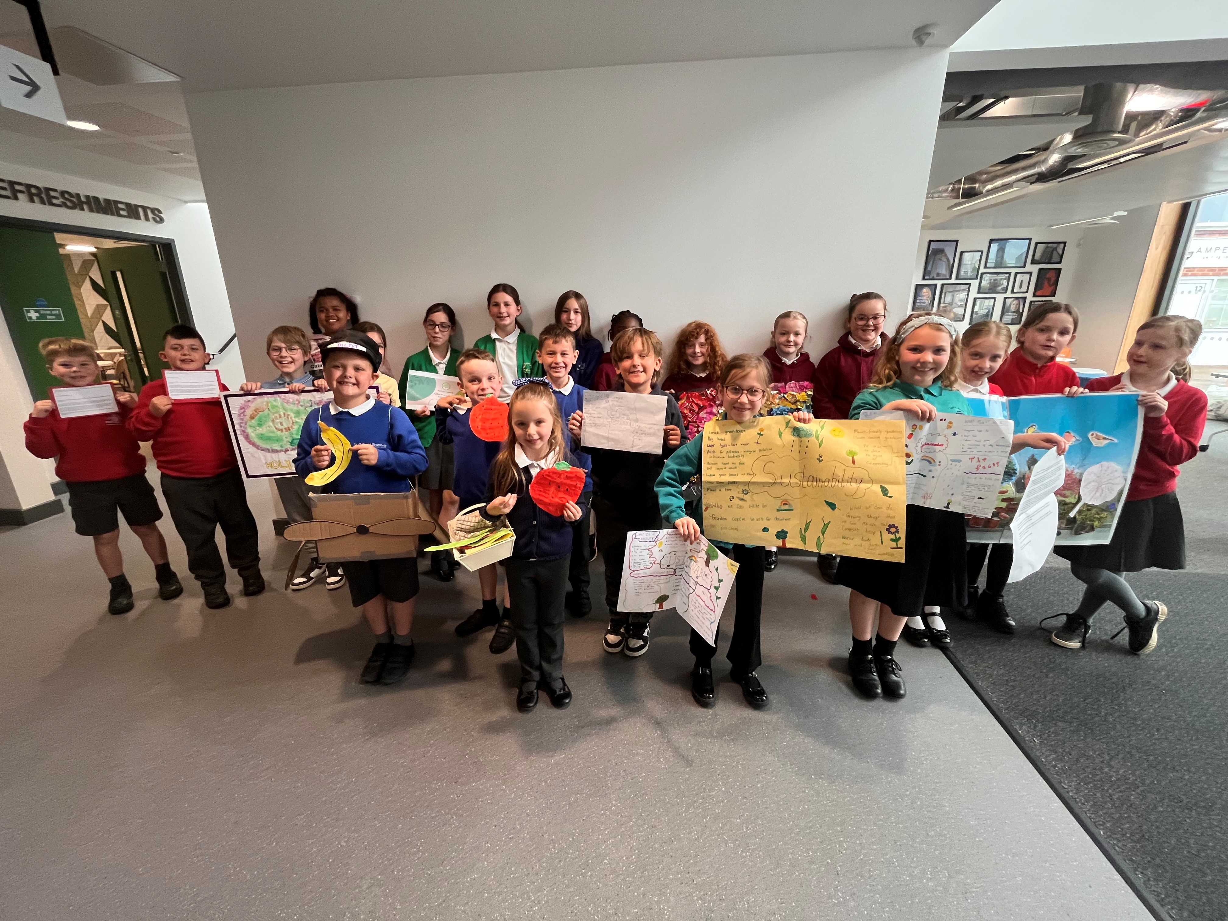 A large group of schoolchildren looking excited, some holding work they have used to support their pitches