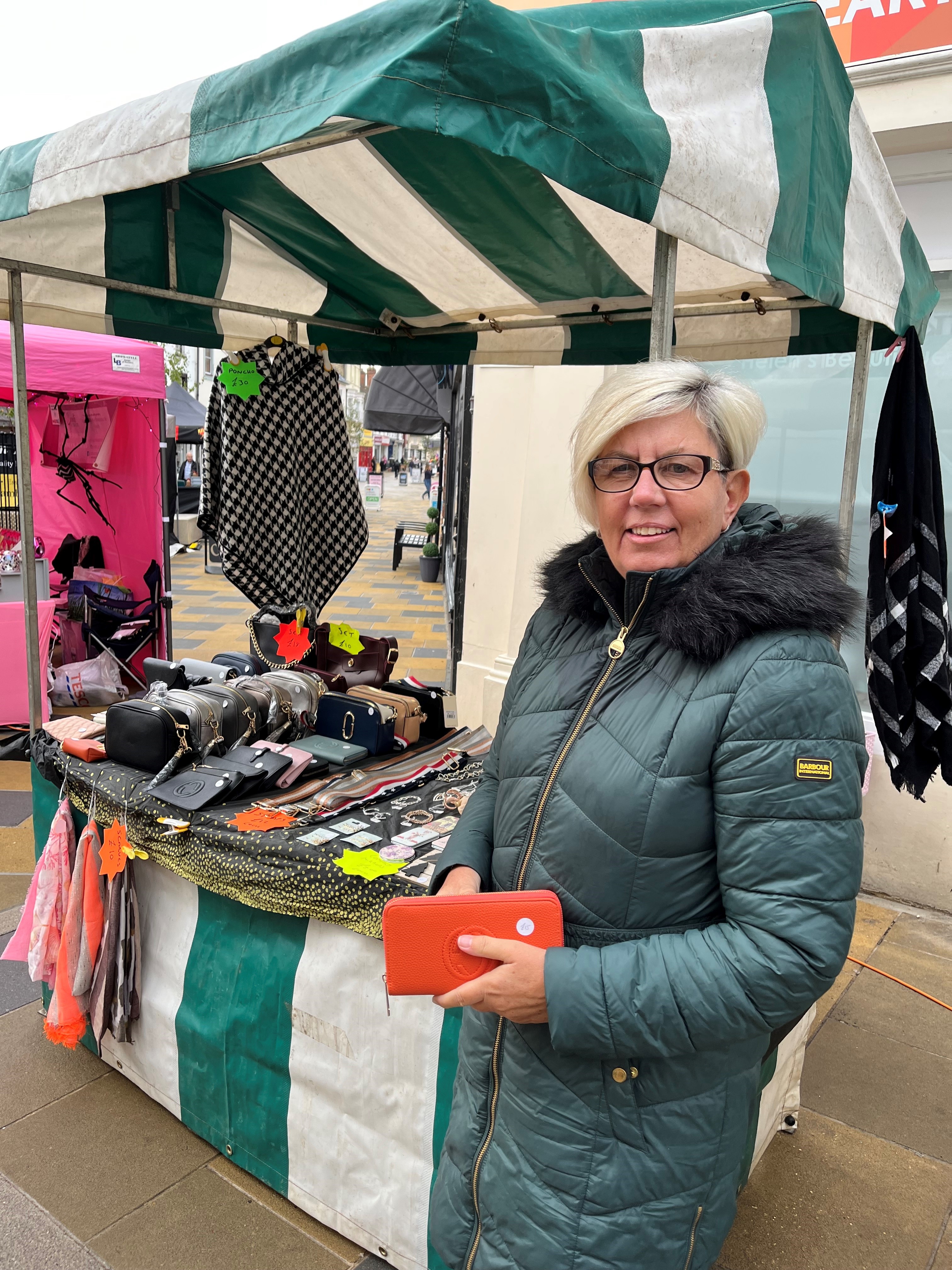 Woman stood in front of green and white stripe market stall at braintree market