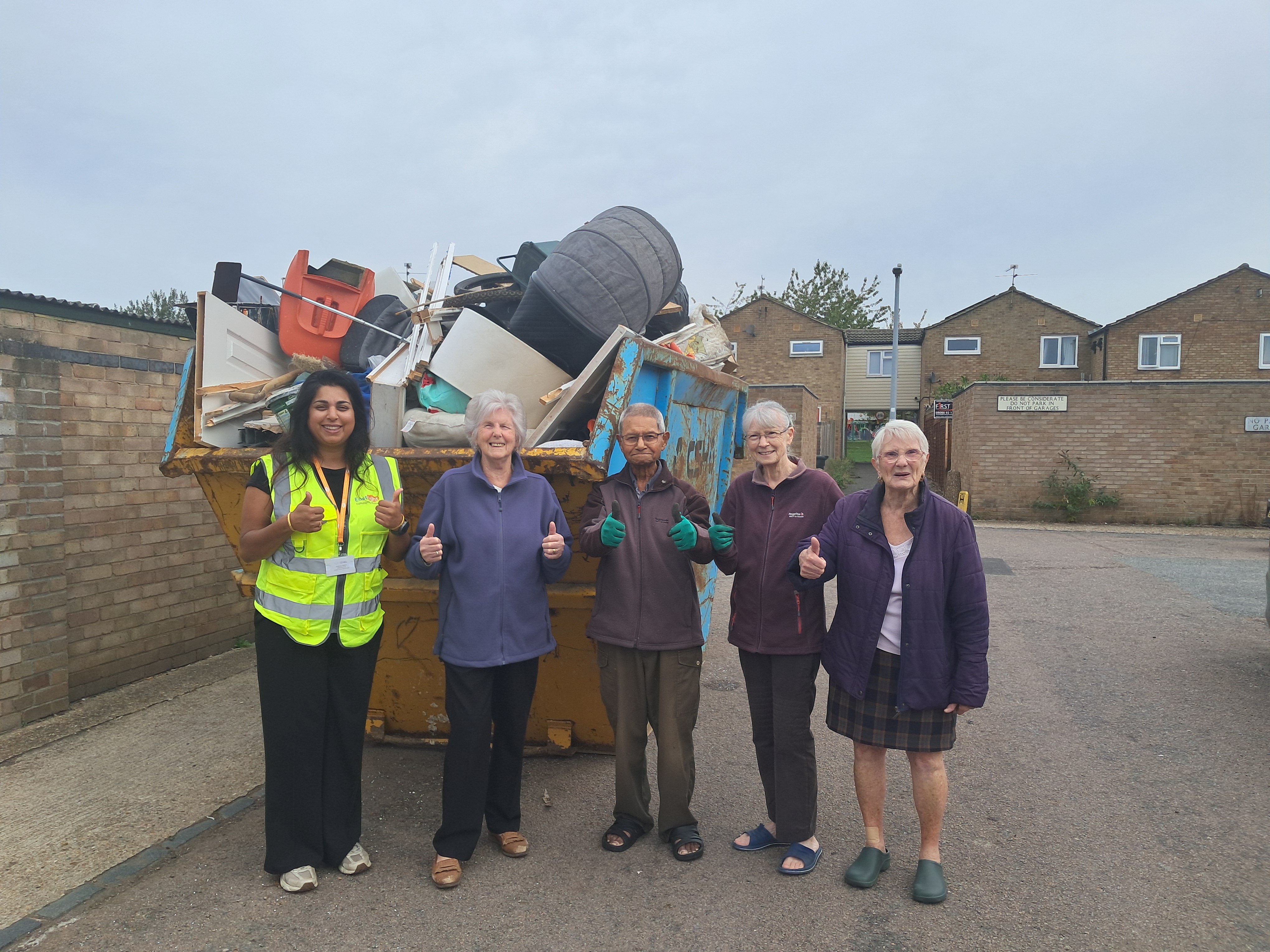 Group of officers and residents standing in front of a skip.