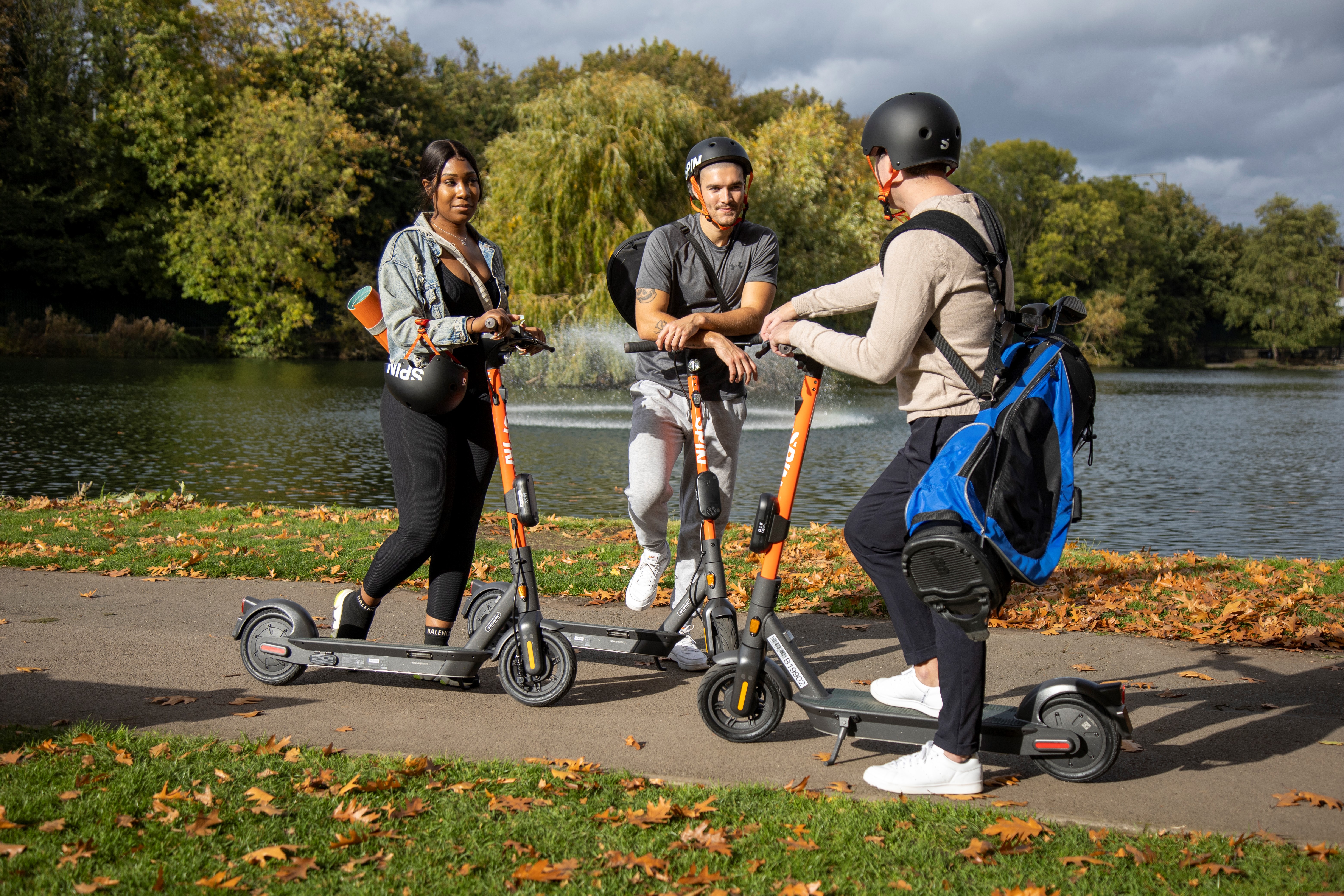 Three people on e-scooters talking on a pathway