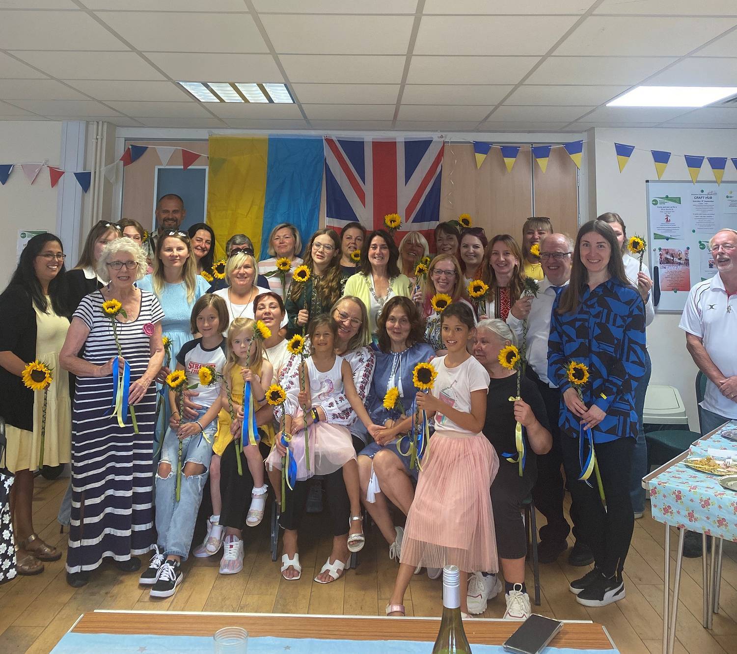 People standing holding sunflowers smiling in a room - Image