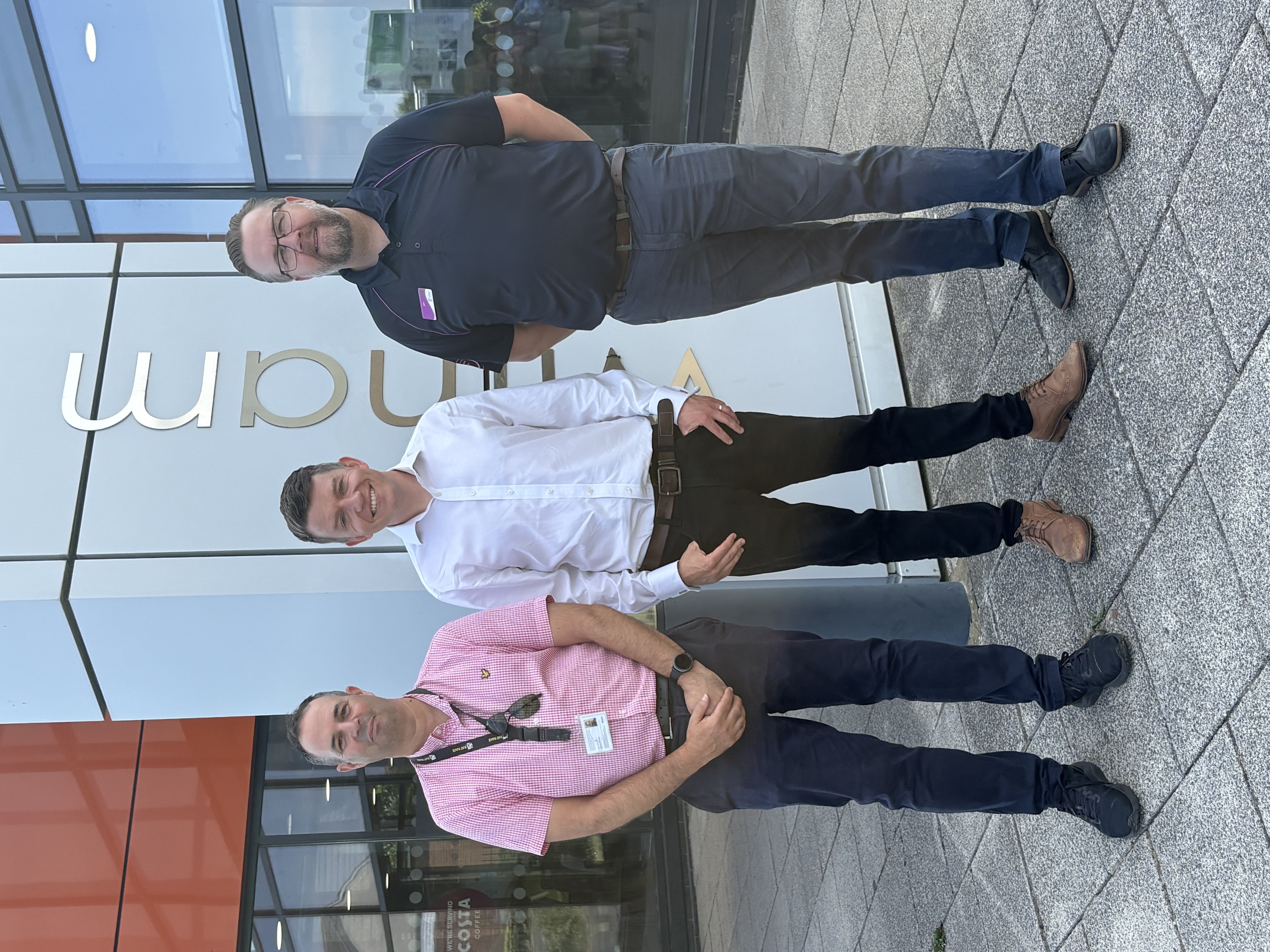 The image shows three people standing in front of a building with a sign stating Witham Leisure Centre
