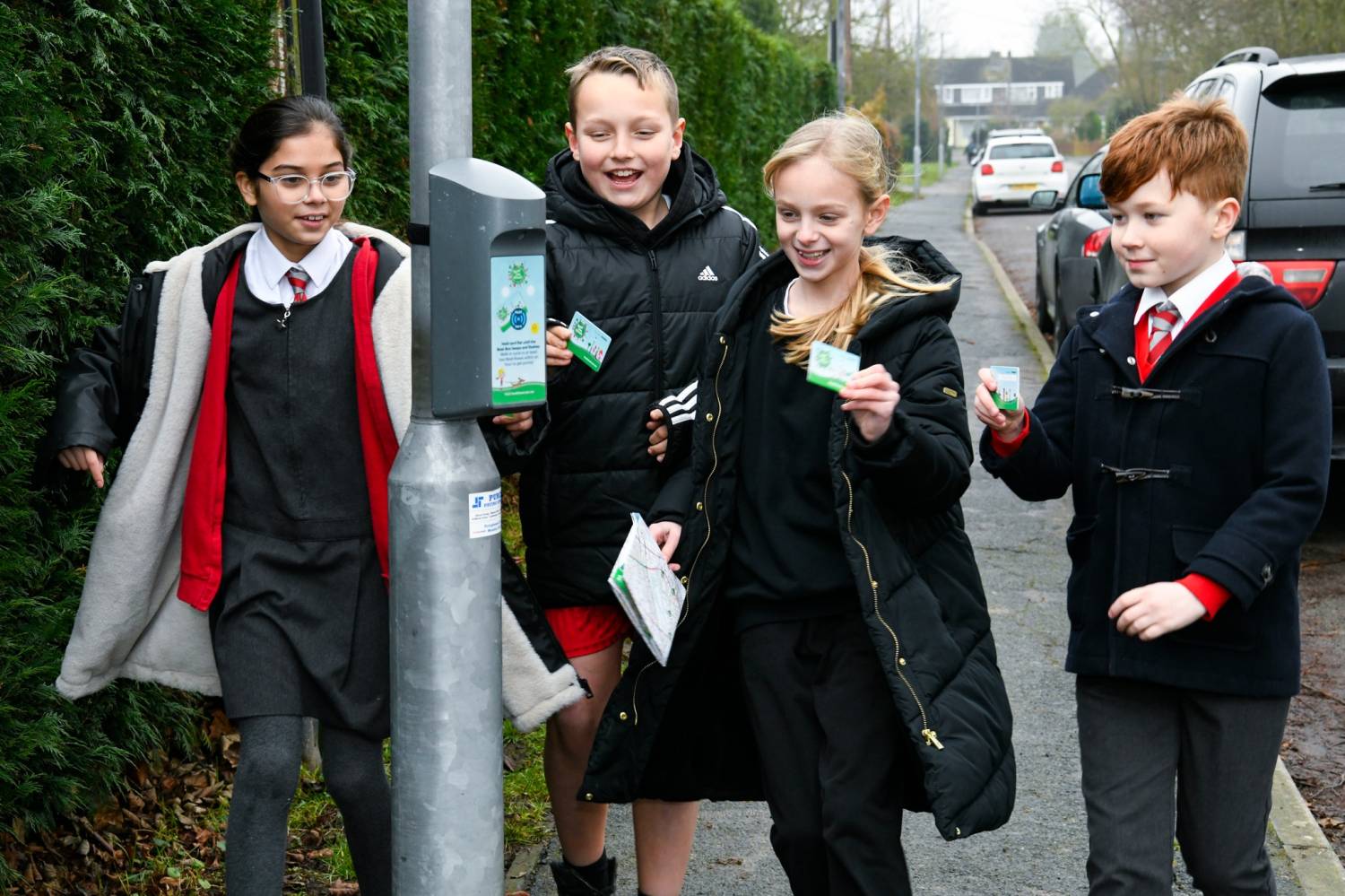 The image shows four children in school uniform and coats standing at a lamppost with the Beat the Street cards.