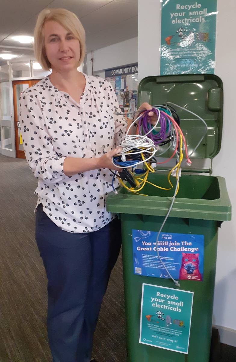 image shows female holding numerous electrical cables about to place them in a WEEE recycling bin