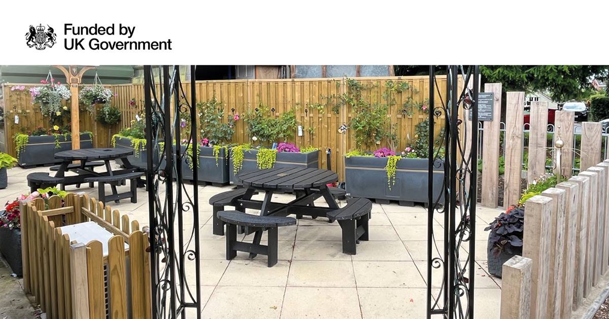 A fenced off area with garden beds planted