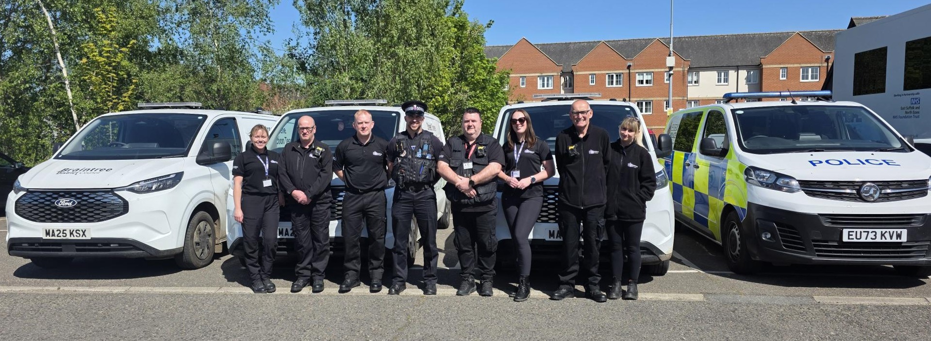 Group photo of street scene protection team and local police officer in front of their branded vehicles.