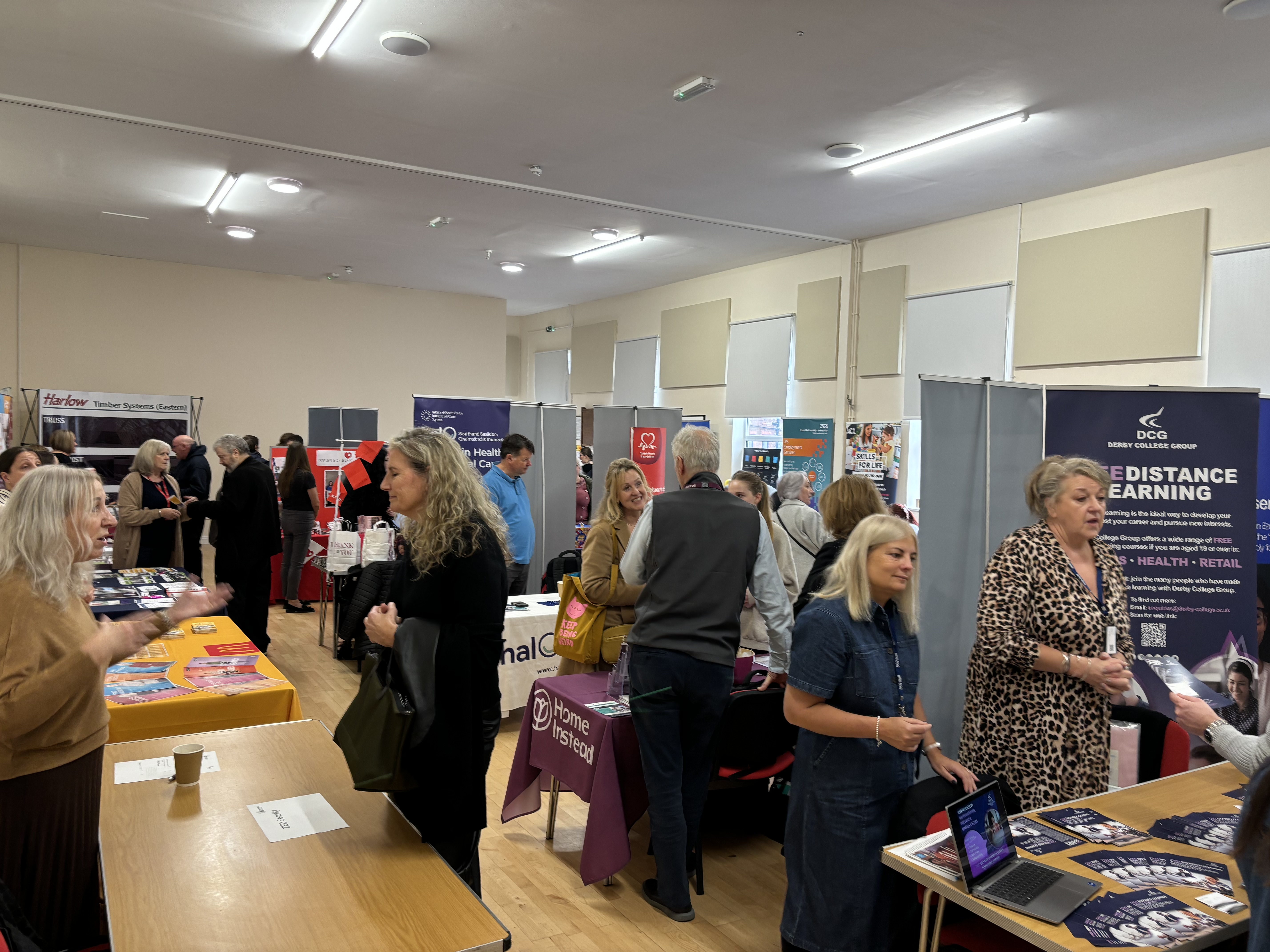 Busy Queen's Hall with stall holders and attendees at a job fair.
