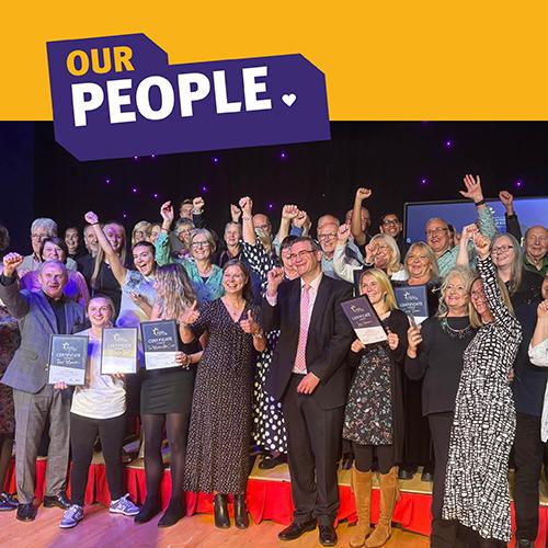 Our people tile with image group of people on stage cheering holding awards